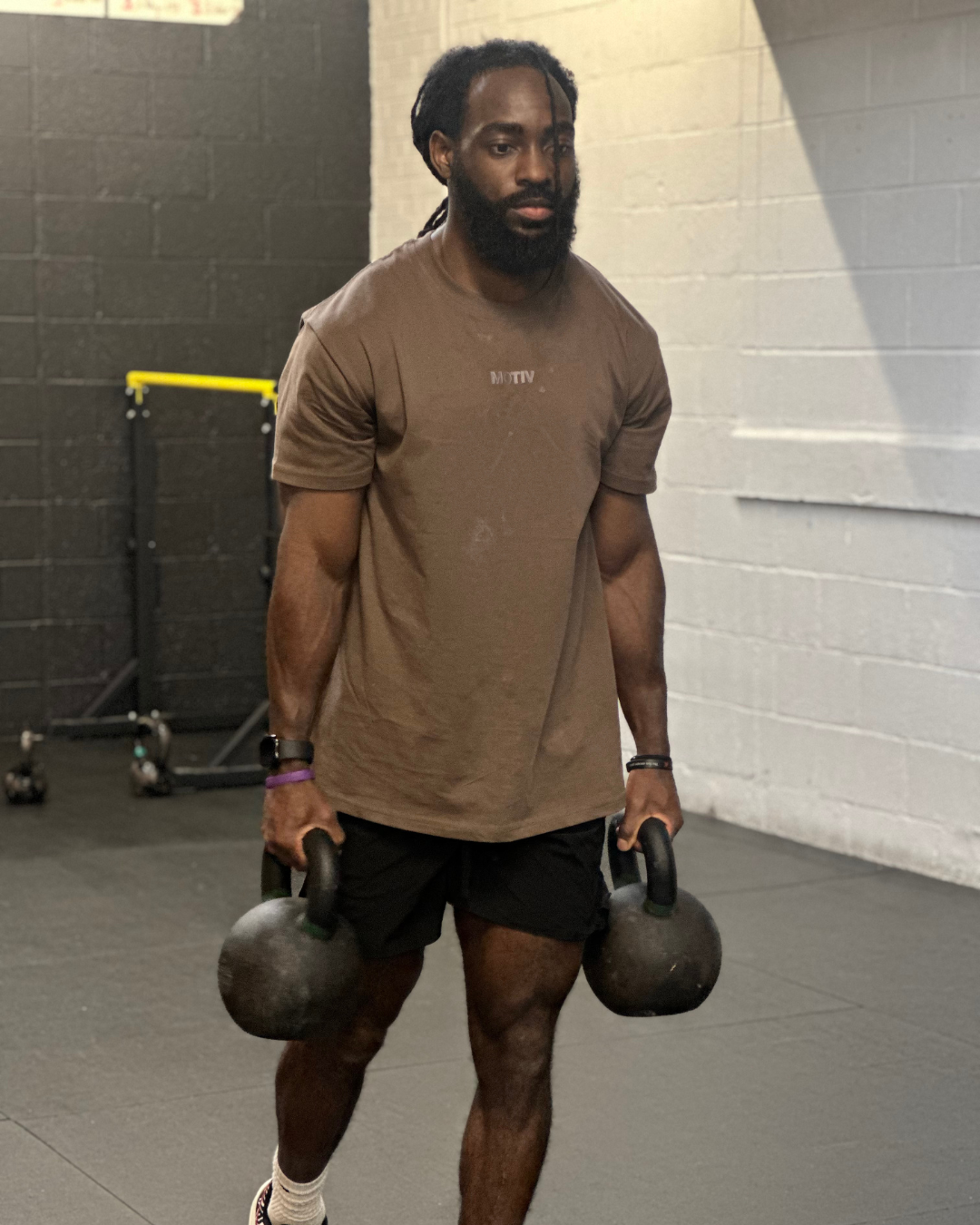 Man holding two kettlebells in a gym setting